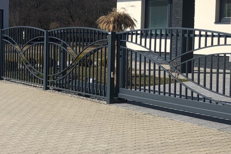     vstupne brany s dekoratívnym kovaným vzorom a bránkou pri rodinnom dome