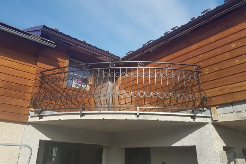 kovane zabradlie na balkon v dekoratívnom prevedení pri drevenom obklade domu